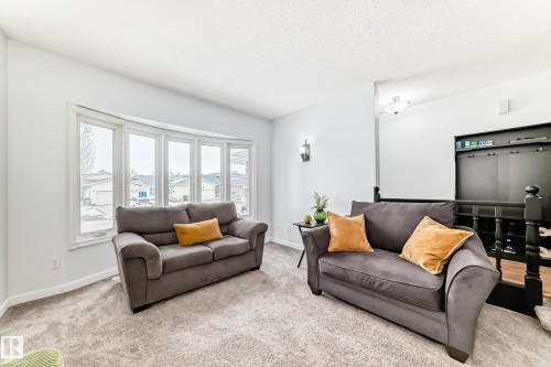 Living area with light-colored carpeting, a large bay window, and a dark-toned railing - 17819 91A Street, Edmonton, AB - Indoor Photo Showing Living Room