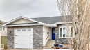 The property features a stone facade, a white garage door with decorative hardware, and a vibrant blue entry door - 17819 91A Street, Edmonton, AB  - Outdoor 