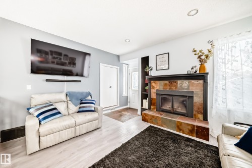 This inviting living area features light-toned flooring and a fireplace with a decorative tile surround - 17819 91A Street, Edmonton, AB - Indoor Photo Showing Living Room With Fireplace