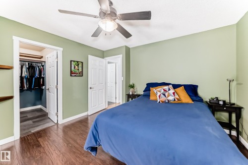 This room features wood flooring, light green walls, a ceiling fan with integrated lighting, and a closet with a bifold door - 17819 91A Street, Edmonton, AB - Indoor Photo Showing Bedroom