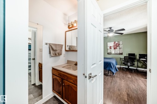 This property features a bathroom with a wood vanity and a mirror cabinet, and a room with wood flooring and a ceiling fan - 17819 91A Street, Edmonton, AB - Indoor