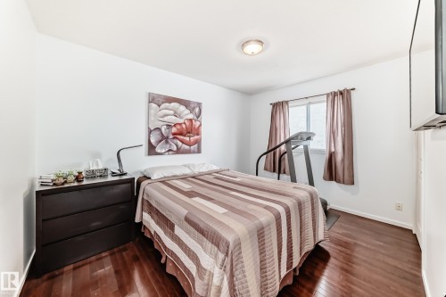 This room features hardwood floors, a ceiling light fixture, a window with curtains, and a wall-mounted display - 17819 91A Street, Edmonton, AB - Indoor Photo Showing Bedroom