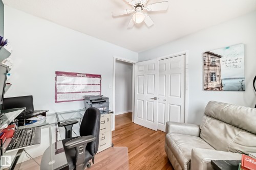 This space features hardwood flooring, white bi-fold closet doors, and a ceiling fan with integrated lighting - 17819 91A Street, Edmonton, AB - Indoor Photo Showing Office