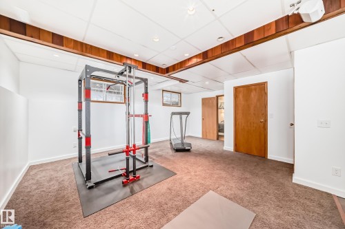 This versatile room features carpeted floors, white walls, and wood trim detailing along the ceiling - 17819 91A Street, Edmonton, AB - Indoor