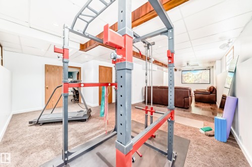 Versatile space featuring a drop ceiling, wood beam accents, and different flooring types including carpet and what appears to be wood flooring - 17819 91A Street, Edmonton, AB - Indoor Photo Showing Gym Room