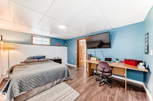 This room features a neutral color palette with blue walls, wood-style flooring, and a drop ceiling - 17819 91A Street, Edmonton, AB - Indoor