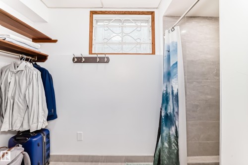This area features a built-in wooden shelf with a hanging rod, a coat rack with four hooks, and a window with a wooden frame and decorative security bars - 17819 91A Street, Edmonton, AB - Indoor