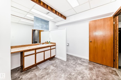 Bathroom featuring a vanity with a white countertop and a single sink, a mirror, and a window with blinds - 17819 91A Street, Edmonton, AB - Indoor