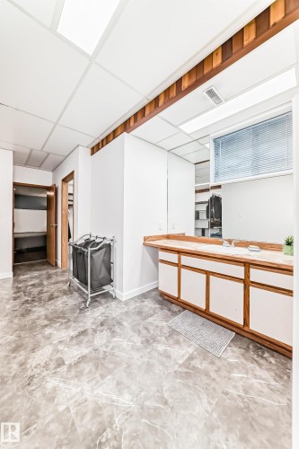 This space features a vanity with a light-colored countertop and a mirror above it, along with a window fitted with blinds - 17819 91A Street, Edmonton, AB - Indoor