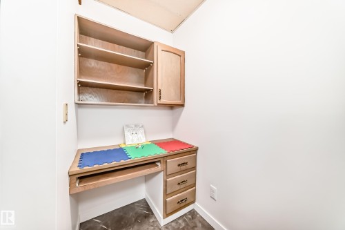 This space features a built-in wooden desk with drawers and an overhead cabinet with shelving, providing functional storage solutions - 17819 91A Street, Edmonton, AB - Indoor