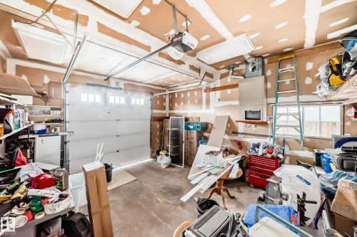 The property includes an attached garage with an overhead door, exposed wall studs, and a window providing natural light - 17819 91A Street, Edmonton, AB - Indoor Photo Showing Garage
