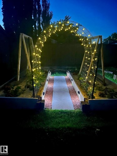 The property features a landscaped backyard with raised garden beds and a lighted archway - 17819 91A Street, Edmonton, AB - Outdoor