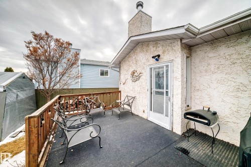 The property features an exterior deck with a wooden railing and a textured stucco wall - 17819 91A Street, Edmonton, AB - Outdoor With Exterior