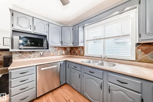 The kitchen features light blue cabinetry with dark hardware, light countertops, and a dual stainless steel sink - 17819 91A Street, Edmonton, AB - Indoor Photo Showing Kitchen With Double Sink