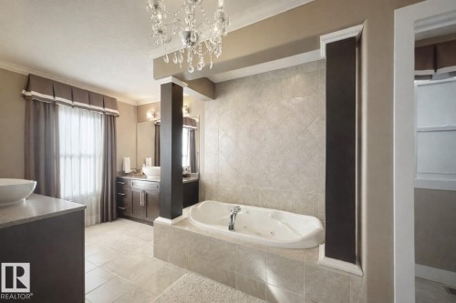 Well-appointed bathroom featuring a jetted bathtub, tiled flooring, and a crystal chandelier - 6712 18 Ave Sw Sw, Edmonton, AB - Indoor Photo Showing Bathroom