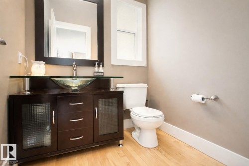 The bathroom features hardwood floors, a dark wood vanity with a glass vessel sink, and a large mirror - 6712 18 Ave Sw Sw, Edmonton, AB - Indoor Photo Showing Bathroom