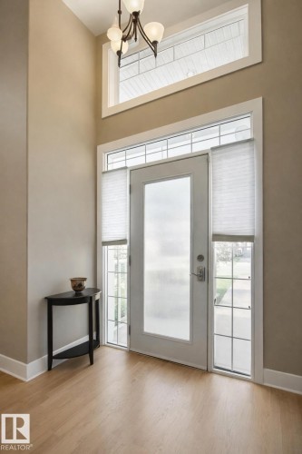 Inviting entryway featuring light-toned flooring, a tall ceiling, and an overhead light fixture - 6712 18 Ave Sw Sw, Edmonton, AB - Indoor Photo Showing Other Room