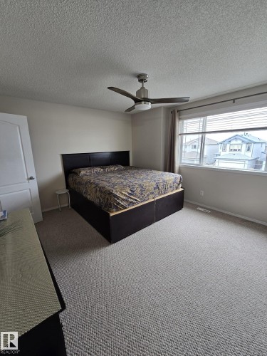 This room features light-colored carpeting, a window with blinds and curtains, and a ceiling fan with integrated lighting - 3311 21 Street, Edmonton, AB - Indoor Photo Showing Bedroom