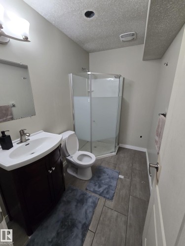 This bathroom features a contemporary vanity with a white sink, a corner glass-enclosed shower, and tile flooring - 3311 21 Street, Edmonton, AB - Indoor Photo Showing Bathroom