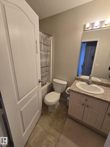 Bathroom featuring a single vanity with a countertop, a toilet, and a bathtub with a shower - 3311 21 Street, Edmonton, AB - Indoor Photo Showing Bathroom