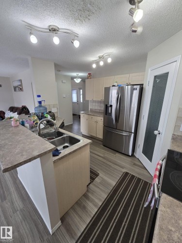 The kitchen features light-colored cabinetry, a double basin sink, and a stainless steel refrigerator - 3311 21 Street, Edmonton, AB - Indoor Photo Showing Kitchen With Double Sink