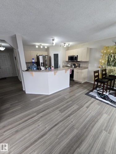 The kitchen features stainless steel appliances, light-toned cabinetry, and a pantry with a frosted glass door - 3311 21 Street, Edmonton, AB - Indoor Photo Showing Other Room