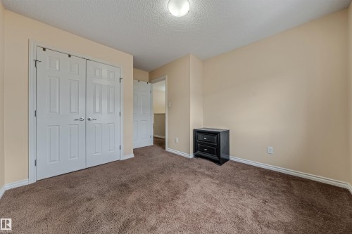This room features a neutral color palette, plush brown carpeting, and white bi-fold closet doors - 2314 22 Avenue, Edmonton, AB - Indoor