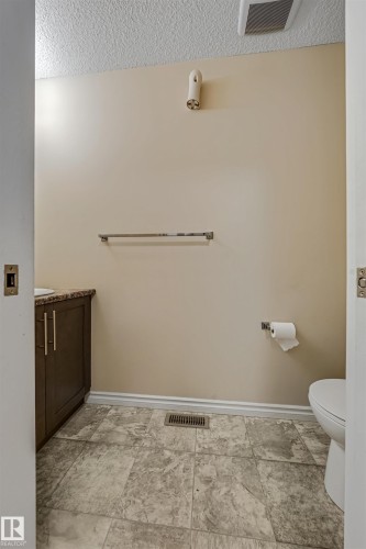 The bathroom features textured flooring, a vanity with a dark wood cabinet and a light-colored countertop, and a white toilet - 2314 22 Avenue, Edmonton, AB - Indoor Photo Showing Bathroom