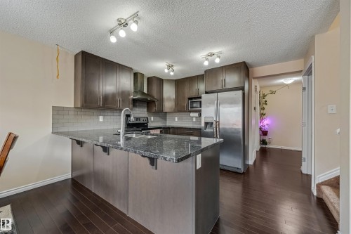 The kitchen features dark wood cabinetry, a grey subway tile backsplash, and stainless steel appliances - 2314 22 Avenue, Edmonton, AB - Indoor Photo Showing Kitchen With Double Sink With Upgraded Kitchen