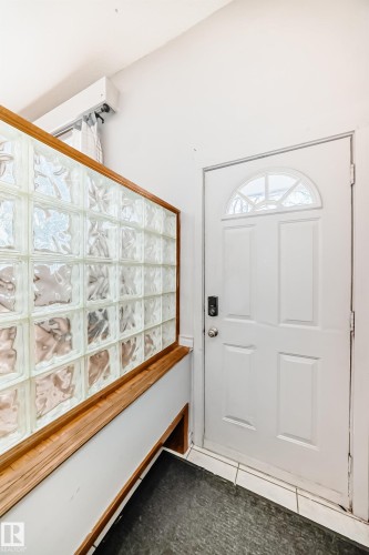 Entryway featuring a white door with an arched window, a glass block wall with a wood frame, and tiled flooring - 12411 126 Street Nw, Edmonton, AB - Indoor Photo Showing Other Room