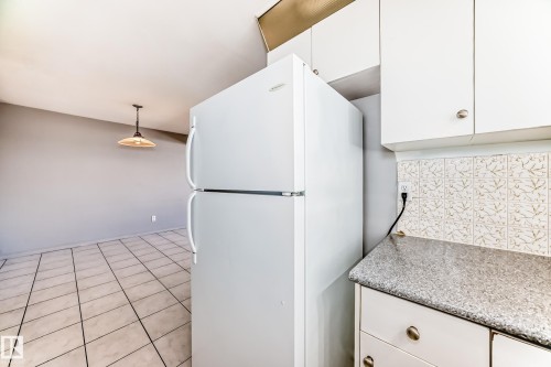 The kitchen features white cabinetry, a light-colored countertop, and a tiled backsplash - 12411 126 Street Nw, Edmonton, AB - Indoor Photo Showing Kitchen
