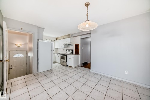 Kitchen featuring white cabinetry, stainless steel oven, a white refrigerator, and tiled flooring - 12411 126 Street Nw, Edmonton, AB - Indoor Photo Showing Kitchen