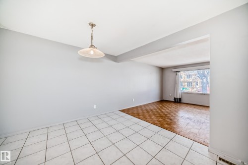 This interior space features light gray walls, a ceiling light fixture, and two distinct flooring types: white square tiles and patterned wood flooring - 12411 126 Street Nw, Edmonton, AB - Indoor Photo Showing Other Room