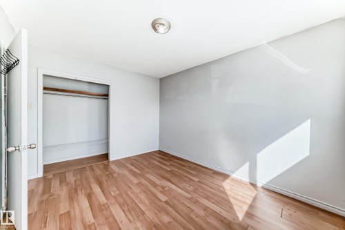 Room featuring wood-look flooring and a closet with a built-in shelf and hanging rod - 12411 126 Street Nw, Edmonton, AB - Indoor Photo Showing Other Room