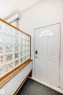 Entryway featuring a white door with an arched window, a glass block wall with a wood frame, and tiled flooring - 12411 126 Street Nw, Edmonton, AB  - Indoor Photo Showing Other Room 