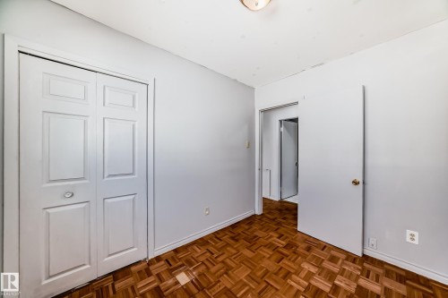 Room featuring patterned wood flooring, a white bi-fold closet door, and a white interior door - 12411 126 Street Nw, Edmonton, AB - Indoor Photo Showing Other Room