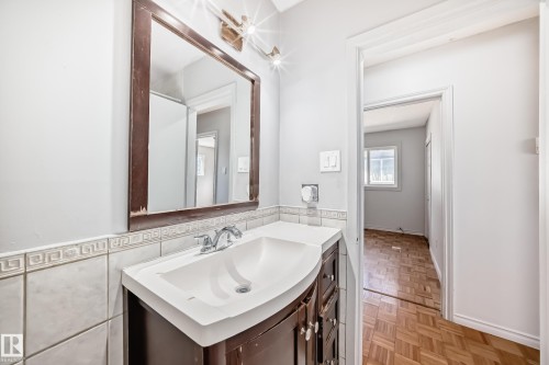 Bathroom vanity with a white countertop and a framed mirror above - 12411 126 Street Nw, Edmonton, AB - Indoor Photo Showing Bathroom