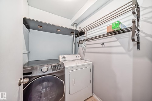 Dedicated laundry area featuring a front-loading washing machine, a dryer, and wall-mounted drying racks - 12411 126 Street Nw, Edmonton, AB - Indoor Photo Showing Laundry Room
