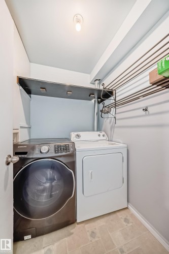 Convenient laundry area featuring a front-loading washing machine, a dryer, and a wall-mounted drying rack - 12411 126 Street Nw, Edmonton, AB - Indoor Photo Showing Laundry Room