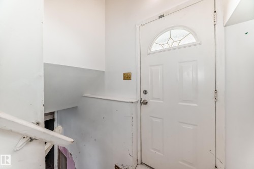 Entryway featuring a white paneled door with an arched window insert and a light-colored handrail - 12411 126 Street Nw, Edmonton, AB - Indoor Photo Showing Other Room