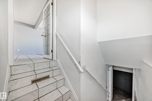 Staircase featuring tiled steps and a white handrail, with a door visible at both the top and bottom - 12411 126 Street Nw, Edmonton, AB - Indoor Photo Showing Other Room