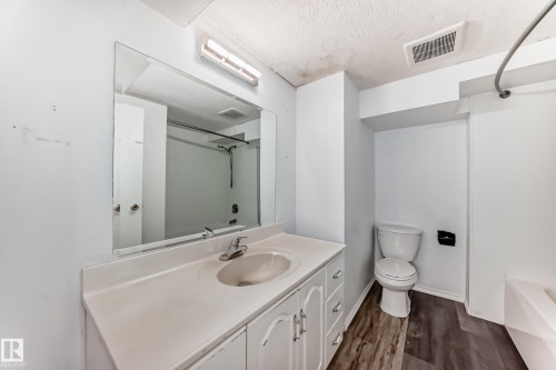 Bathroom featuring a vanity with an integrated sink and mirror, a toilet, and a bathtub with a shower rod - 12411 126 Street Nw, Edmonton, AB - Indoor Photo Showing Bathroom