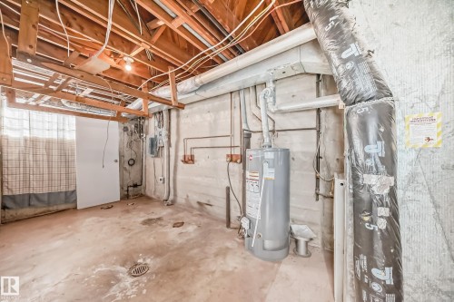 The property includes a utility area with exposed wooden ceiling joists, a water heater, and visible plumbing and ductwork - 12411 126 Street Nw, Edmonton, AB - Indoor Photo Showing Basement