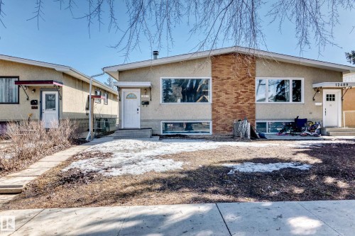The property features a stucco exterior with a brick accent wall and white-framed windows - 12411 126 Street Nw, Edmonton, AB - Outdoor