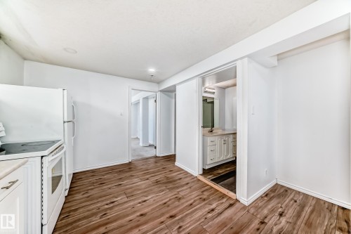 This interior space features wood-style flooring and white walls, creating a bright atmosphere - 12411 126 Street Nw, Edmonton, AB - Indoor Photo Showing Kitchen