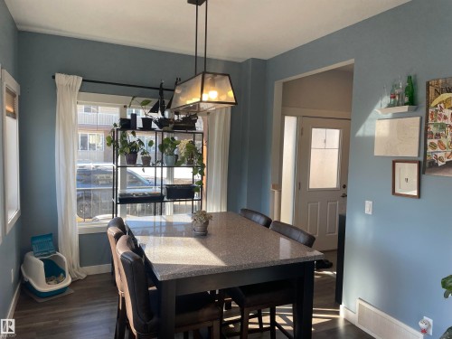 The property features a dining area with a modern light fixture, hard surface flooring, and a window with white curtains - 15220 105 Avenue, Edmonton, AB - Indoor Photo Showing Dining Room