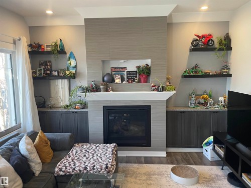 The living area features a built-in fireplace with a mantel, recessed lighting, and built-in shelving and cabinetry for storage - 15220 105 Avenue, Edmonton, AB - Indoor Photo Showing Living Room With Fireplace