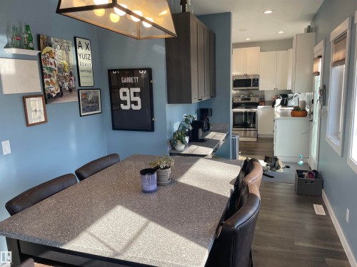 The property features a kitchen with white cabinetry and stainless steel appliances, including a range and microwave - 15220 105 Avenue, Edmonton, AB - Indoor Photo Showing Dining Room
