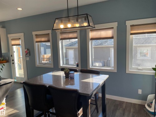 This room features blue walls, wood-look flooring, and a door with a window providing outdoor access - 15220 105 Avenue, Edmonton, AB - Indoor Photo Showing Dining Room