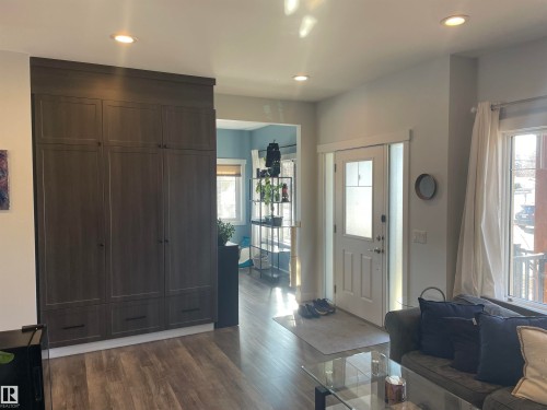The property features recessed ceiling lighting, a white entry door with frosted side panels, and wood-look flooring - 15220 105 Avenue, Edmonton, AB - Indoor Photo Showing Other Room